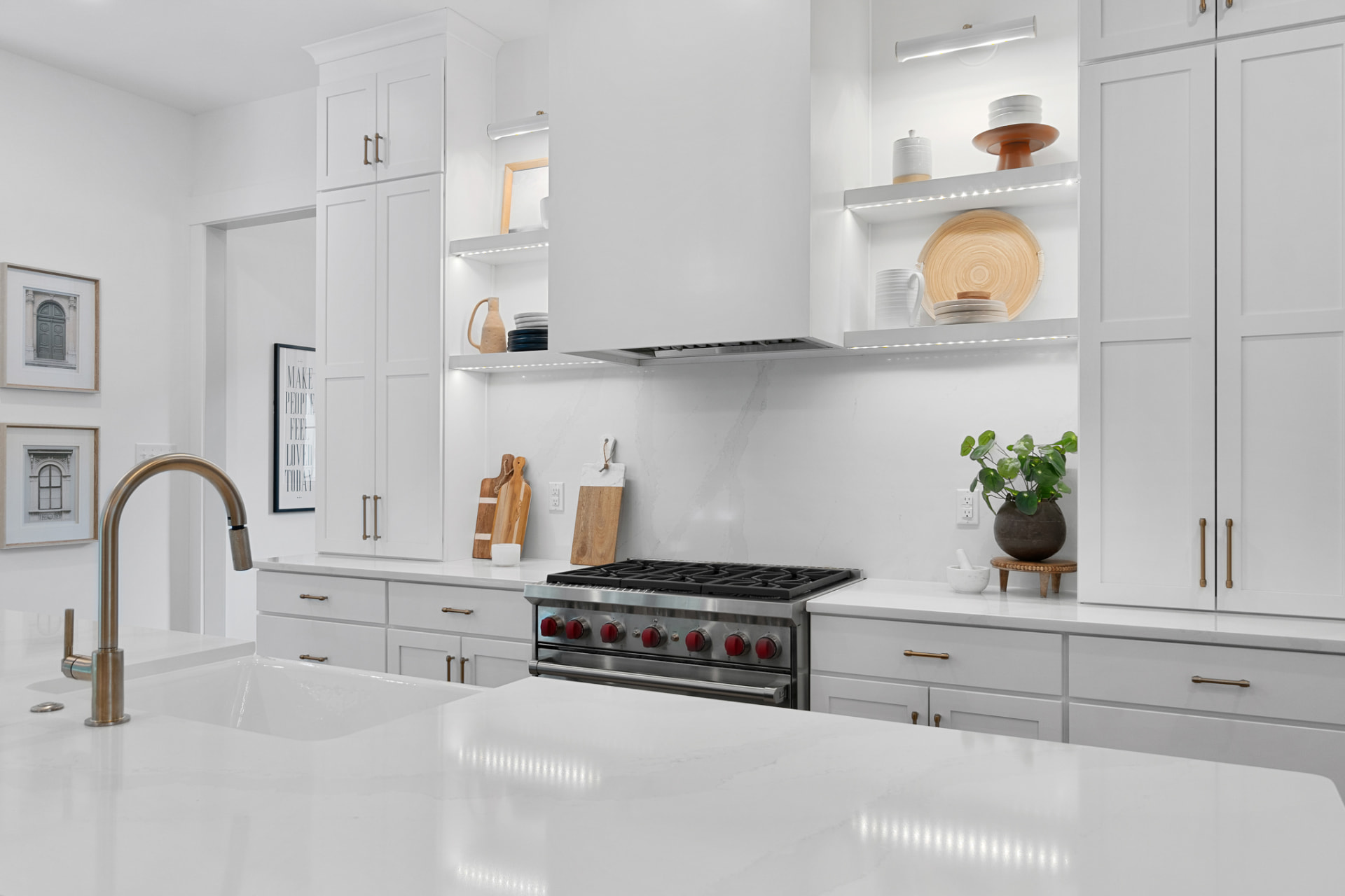White kitchen with lit open shelving and professional range