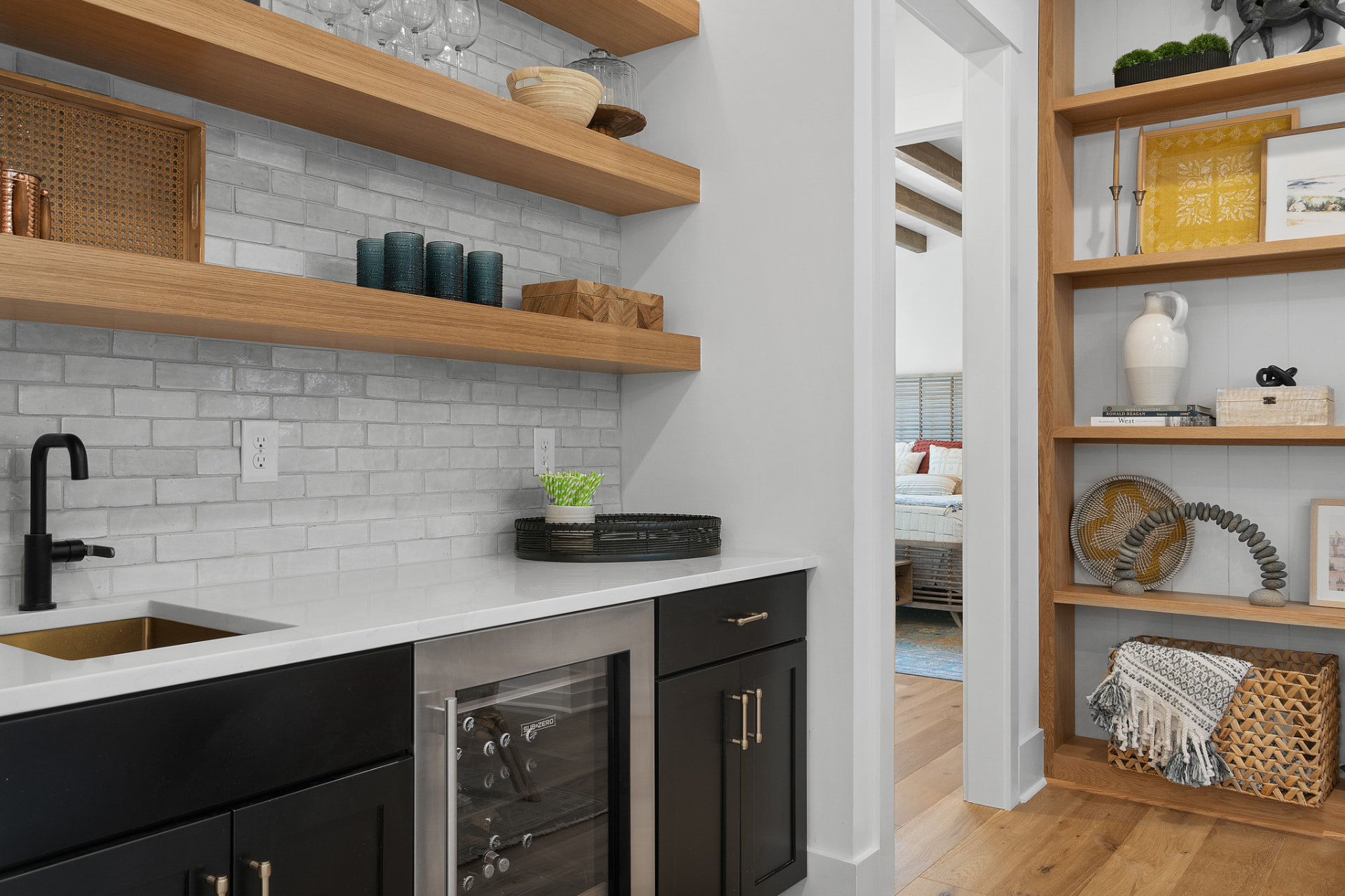 Wet bar with black base cabinets and oak floating shelves