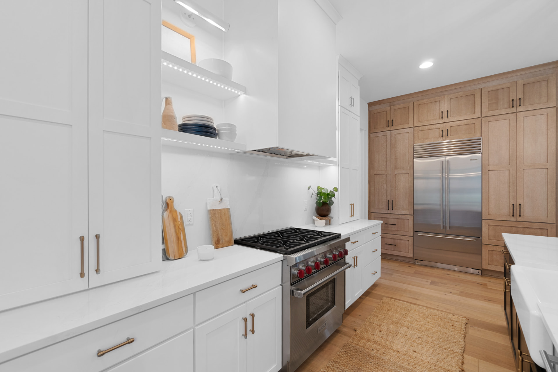 White kitchen opening to a natural-wood tall cabinetry wall